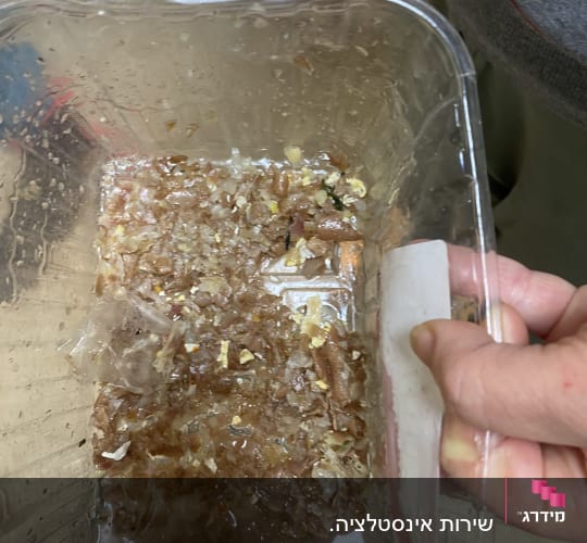יד מחזיקה מיכל עם שאריות מזון ונוזלים